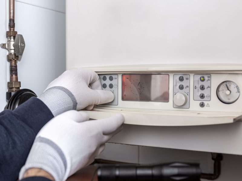 Technician servicing heating boiler in a house. Maintenance concept